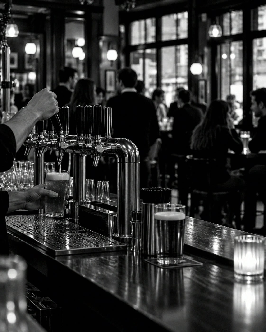 A pint being pulled at a pub's wooden bar, people at the bar and at tables behind.