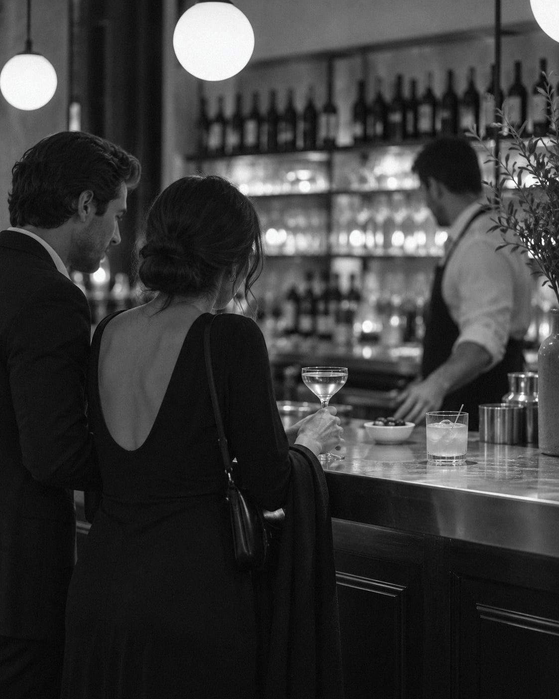 Two guests with a drink at a restaurant bar, waiting for their table.