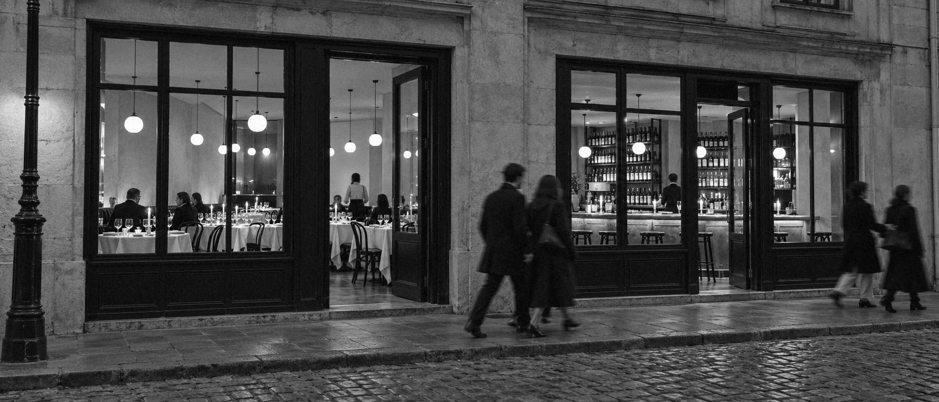 Two small restaurants of the same group side by side on a city street at dusk, both lit and opening for the evening.